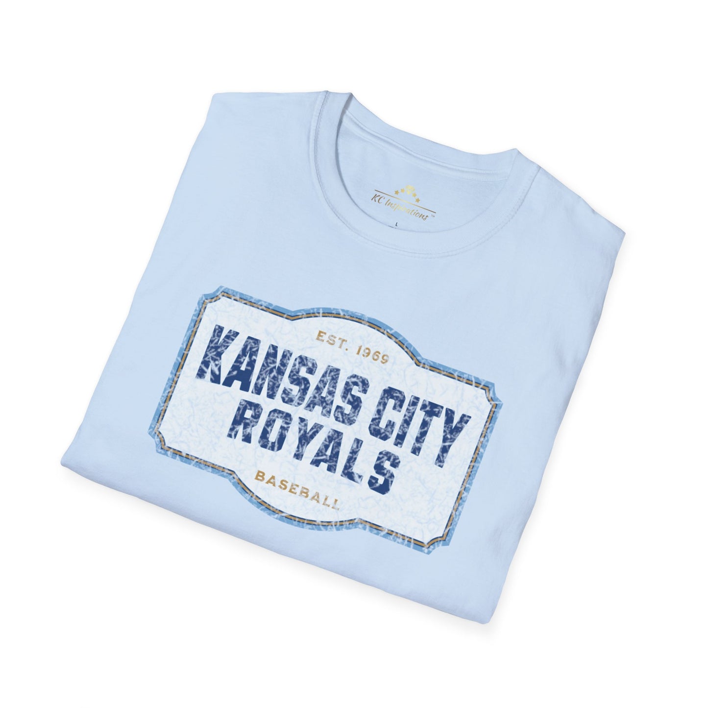 A light blue T-shirt with a graphic label in the center displaying "Kansas City Royals Baseball" in bold blue letters. The text "Est. 1969" is shown above the main text, giving it a vintage throwback look. Perfect for showing team spirit, this distressed T-shirt, Royal Badge - Kansas City Royals Inspired T-Shirt by KC Inspirations, is displayed on a white background.