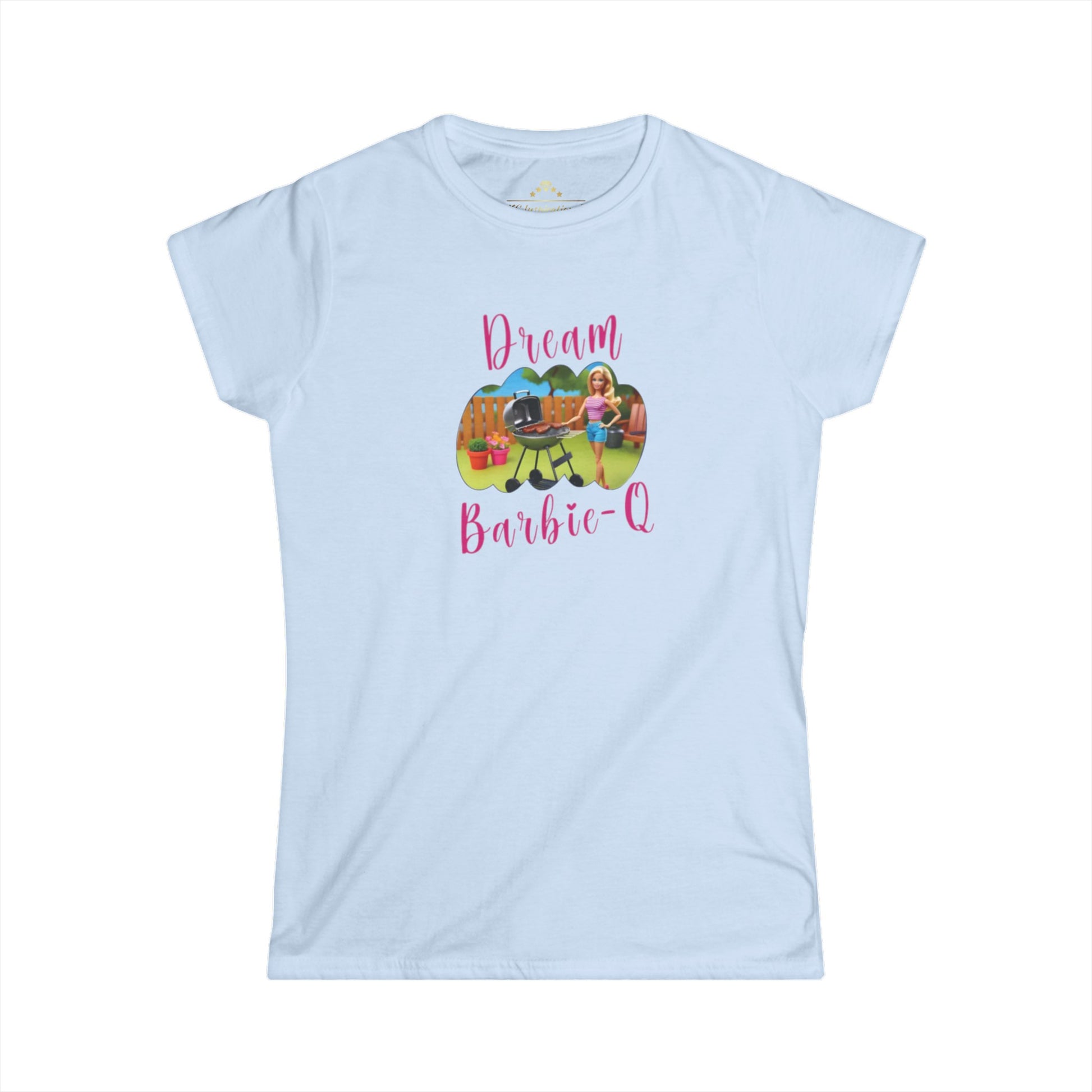 This Dream Barbie-Q - K.C. BBQ Inspired Women's T-Shirt by KC Inspirations is a light blue T-shirt featuring an illustration of a girl beside a grill with food, set against a playful outdoor background. Above the image, "Dream" is written in colorful letters and below it, "Barbie-Q" in whimsical pink font—perfect for fans of Kansas City BBQ.