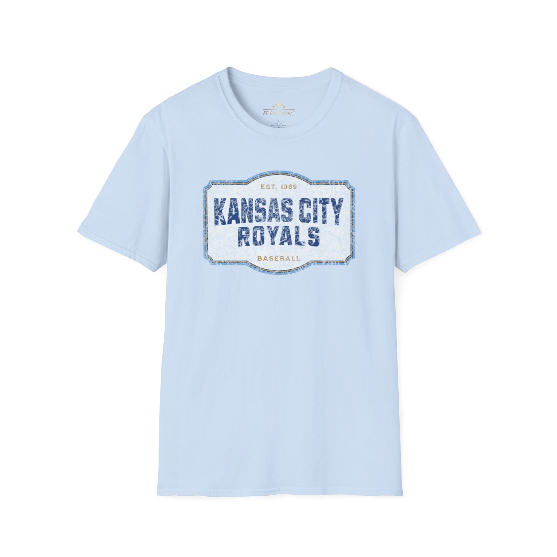 A light blue T-shirt with a graphic label in the center displaying "Kansas City Royals Baseball" in bold blue letters. The text "Est. 1969" is shown above the main text, giving it a vintage throwback look. Perfect for showing team spirit, this distressed T-shirt, Royal Badge - Kansas City Royals Inspired T-Shirt by KC Inspirations, is displayed on a white background.