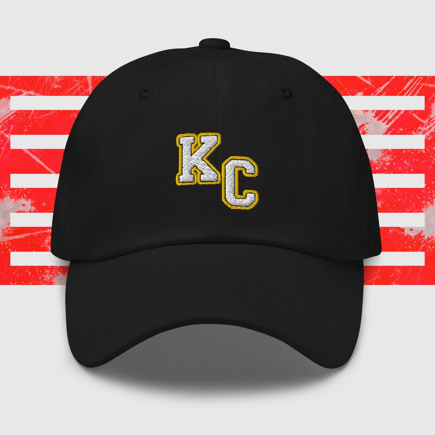 Red KC Inspirations Kansas City Chiefs Inspired Cap with gold letters "KC" embroidered on the front. The background features a stylized American flag with red stripes and white stars, appearing distressed or splattered with paint. This KC White & Gold - Kansas City Chiefs Inspired Cap comes with an adjustable strap and has a curved brim.