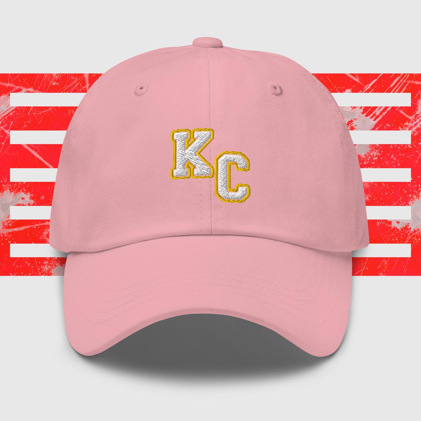 Red KC Inspirations Kansas City Chiefs Inspired Cap with gold letters "KC" embroidered on the front. The background features a stylized American flag with red stripes and white stars, appearing distressed or splattered with paint. This KC White & Gold - Kansas City Chiefs Inspired Cap comes with an adjustable strap and has a curved brim.